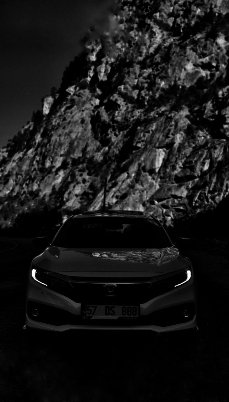 a black and white photo of a car in front of a mountain