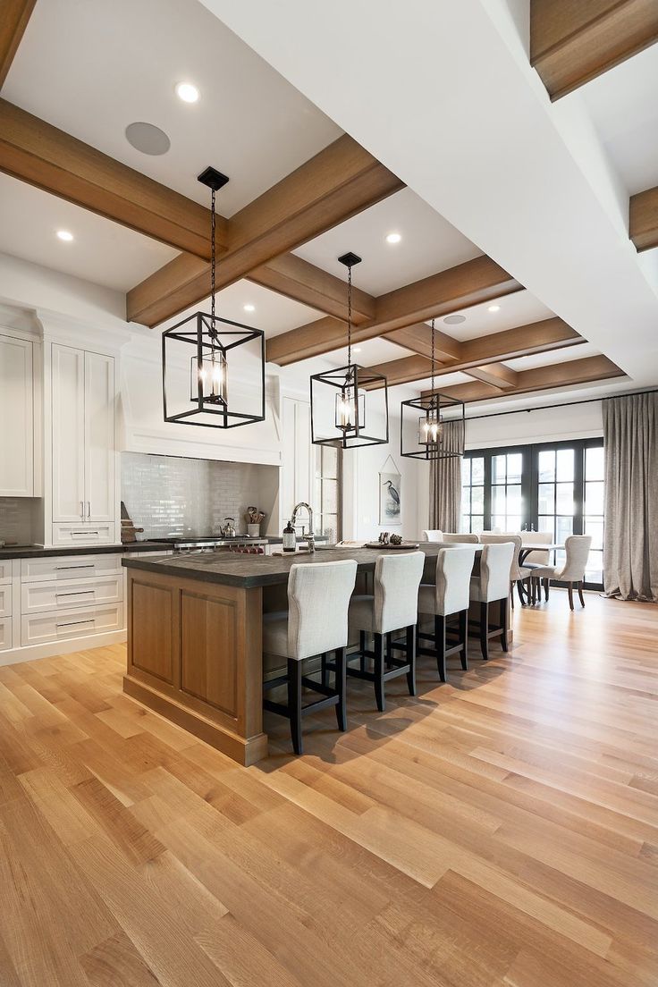 an open kitchen and dining room with white cabinets, wood floors and wooden beams on the ceiling