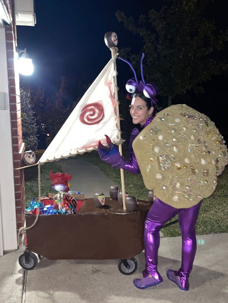 a woman dressed in purple holding a flag and standing next to a cart filled with items