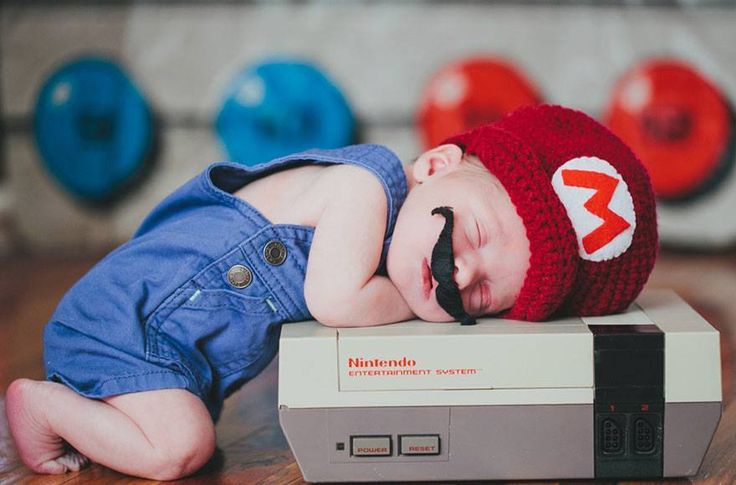 a baby sleeping on top of a nintendo wii game console