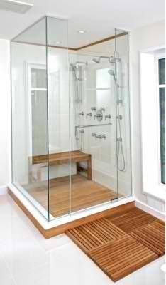 a walk in shower sitting inside of a bathroom next to a wooden floor and white walls