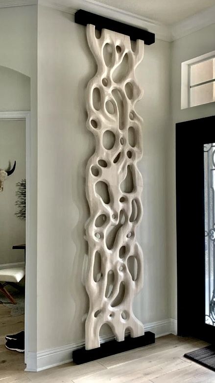 a tall white sculpture sitting in the middle of a living room next to a doorway