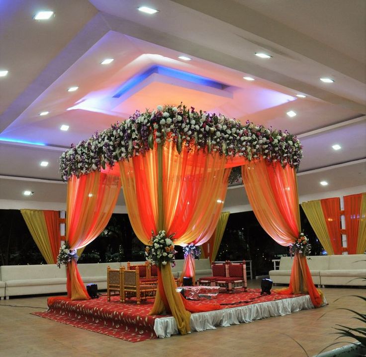 a decorated stage with orange drapes and flowers