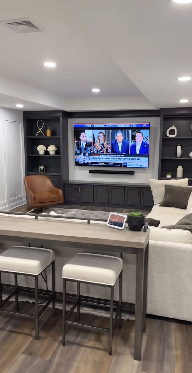 a large entertainment room with two couches and a flat screen tv on the wall