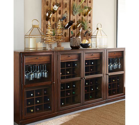 a wooden cabinet with wine glasses and bottles on it in front of a wall mounted art piece