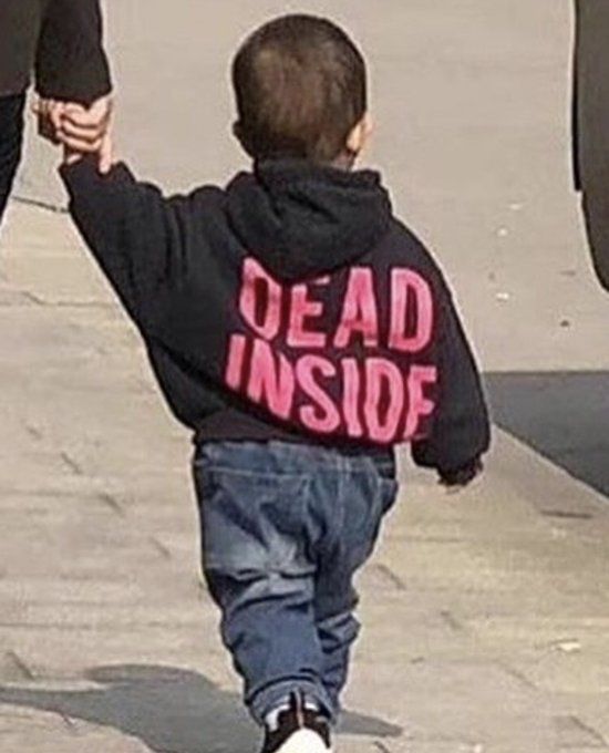 a little boy walking down the sidewalk holding hands with an adult in black leggings