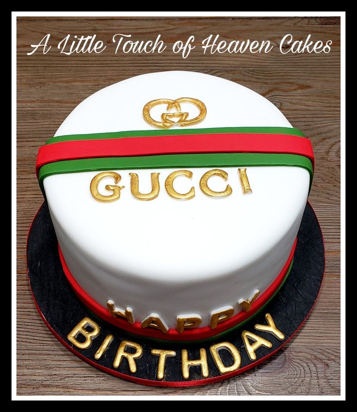 a birthday cake with the name gucci written on it and gold lettering is sitting on a wooden table