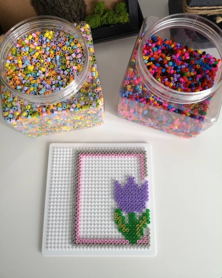 two plastic containers filled with colorful beads next to a square shaped object on top of a table