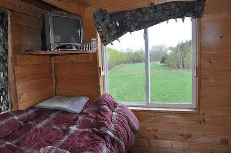 a bed in a room with wooden walls and a tv on top of the wall