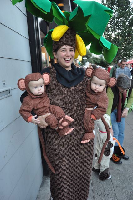 a woman holding two babys wearing monkey costumes