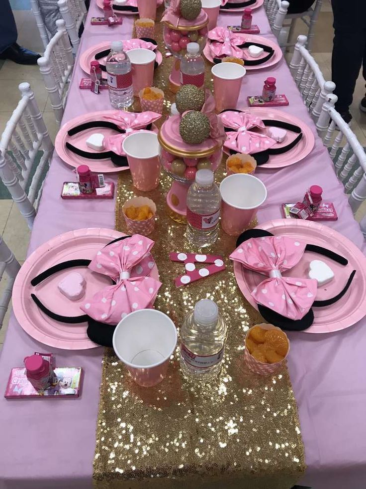 a table set up with pink and gold plates, cups, napkins and utensils