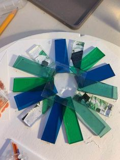 a circular piece of glass sitting on top of a table next to paint and pencils