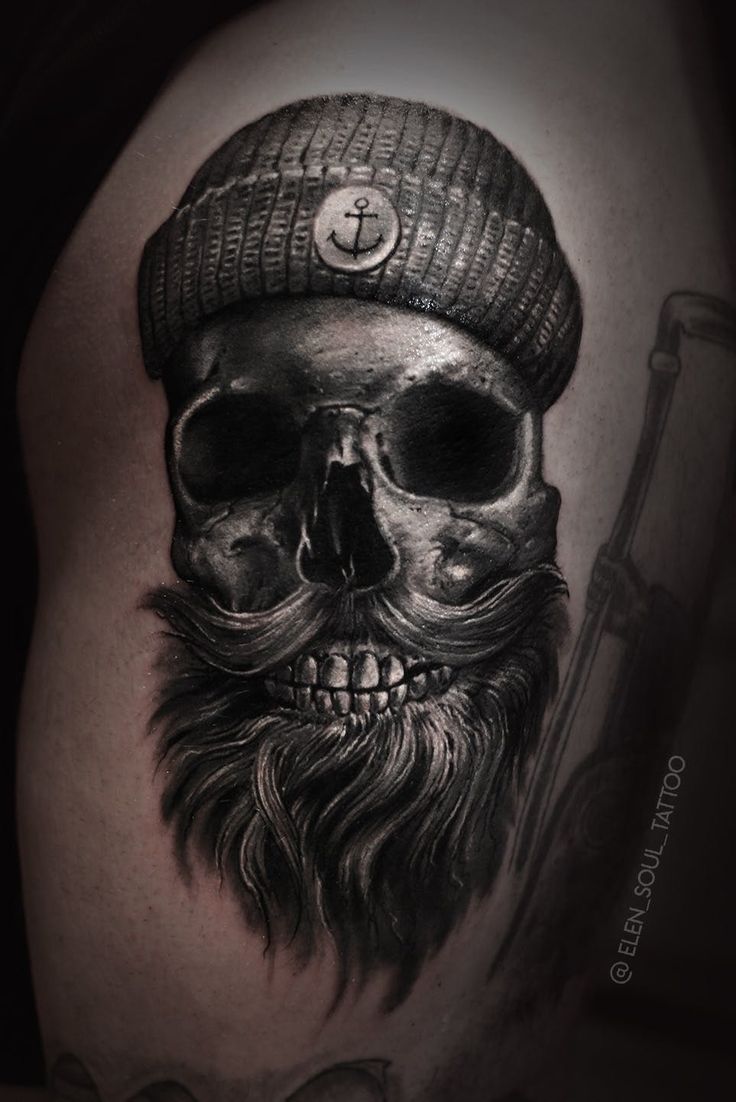 a skull with a hat and beard tattoo on the thigh