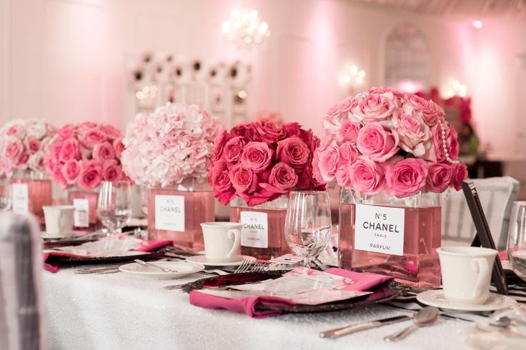 pink flowers are in vases on a table with place cards and silverware for guests to eat