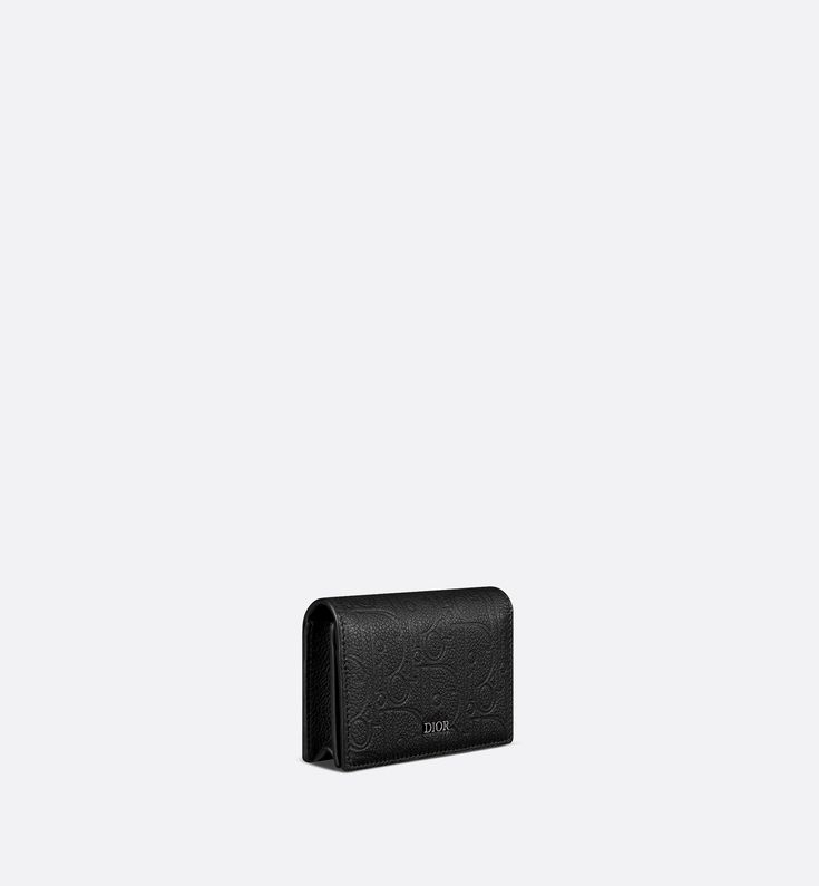 The business card holder is a practical accessory with a sophisticated aesthetic. Displaying the virtuosity of the House ateliers, the Dior Gravity leather showcases the iconic motif delicately embossed on black calfskin and a Dior signature on the front. The style features a gusseted compartment with a slot as well as two card slots on the flap. The business card holder can easily be carried in any pocket or bag.. Luxury Rectangular Card Holder For Evening, Elegant Rectangular Card Holder For Evening, Elegant Rectangular Evening Card Holder, Formal Wallets With Interior Card Slots In Rectangular Case, Luxury Leather Card Holder For Evening, Designer Rectangular Card Holder For Evening, Formal Wallet With Interior Card Slots, Luxury Formal Card Holder With Card Slots, Compact Formal Card Holder With Card Slots