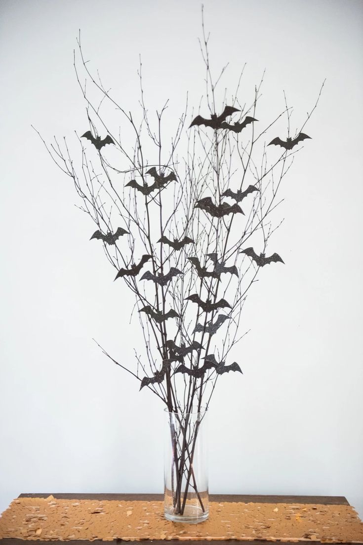 a vase filled with lots of bats sitting on top of a wooden table next to a wall