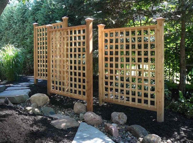 a wooden trellis in the middle of a garden with rocks and gravel around it