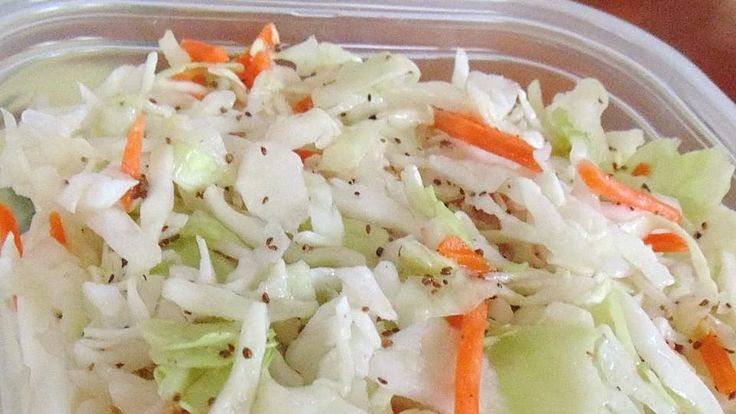 a plastic container filled with coleslaw and carrots on top of a table