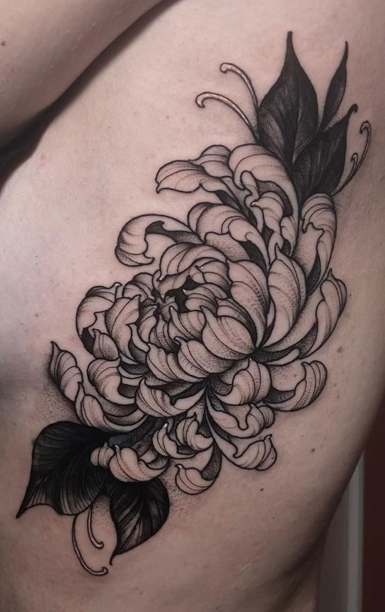 a black and white flower tattoo on the side of a woman's stomach,