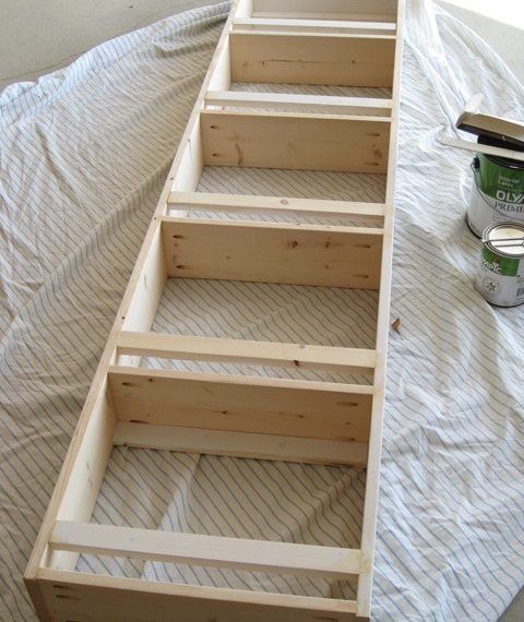 a wooden boat sitting on top of a bed next to a paint can and brush