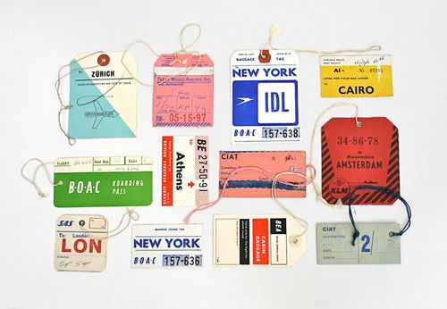 various luggage tags are laid out on a white surface with twine and string attached to them