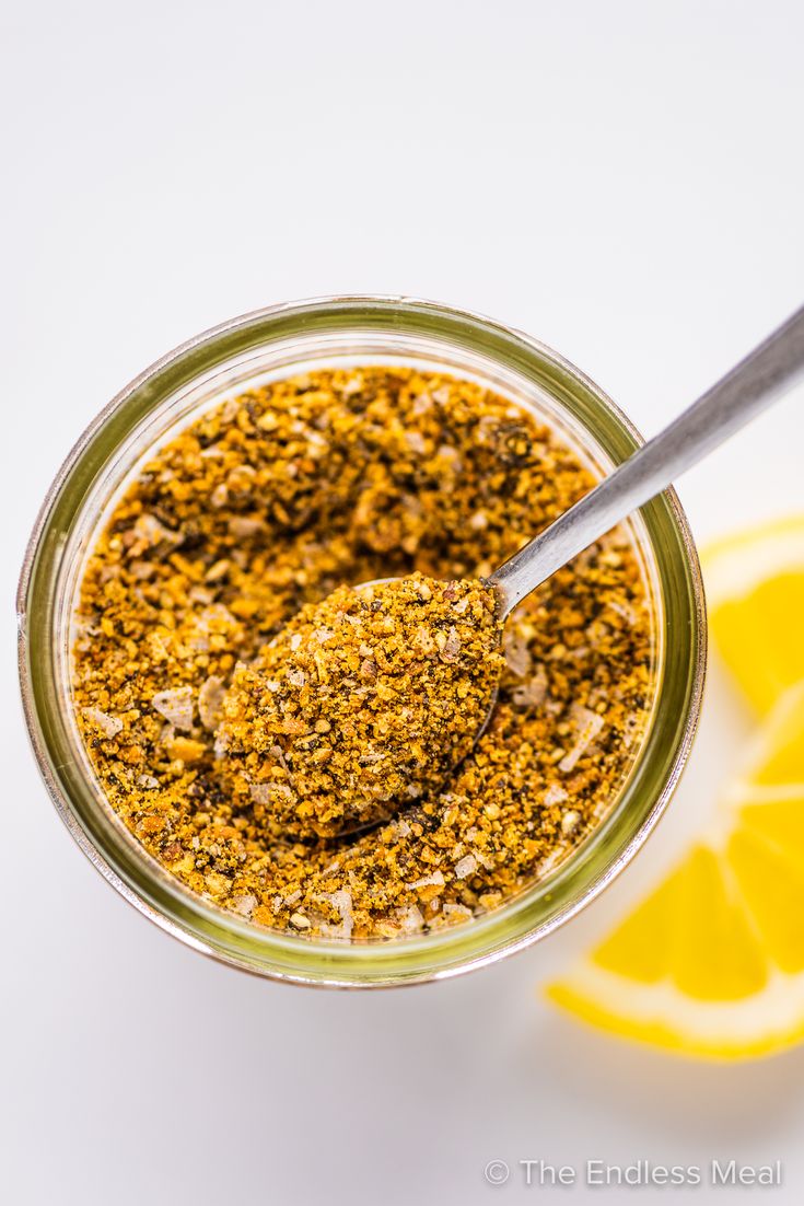 a spoon in a jar filled with food next to lemon wedges and a slice of lime