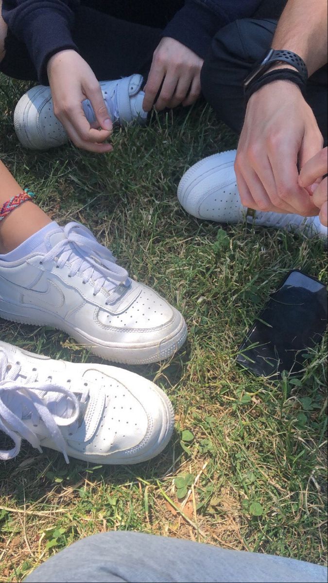 two people sitting on the grass tying their shoes