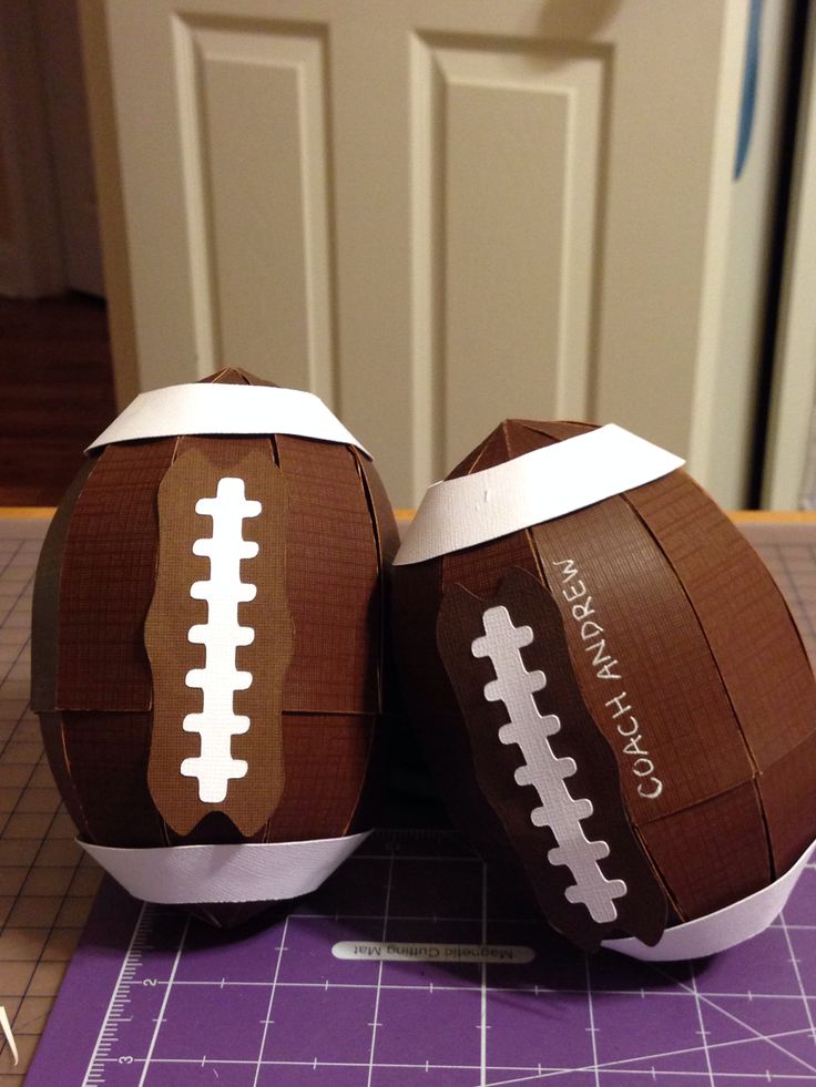 two paper footballs sitting on top of a cutting board