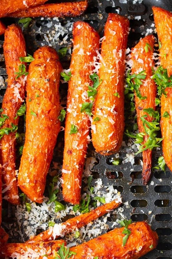 carrots with parmesan cheese and herbs are on a grill grate, ready to be cooked