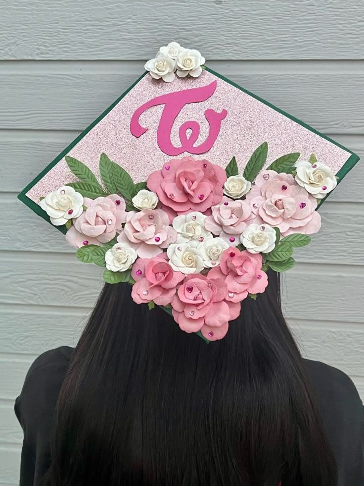 a girl wearing a pink and green graduation cap with flowers on it's head