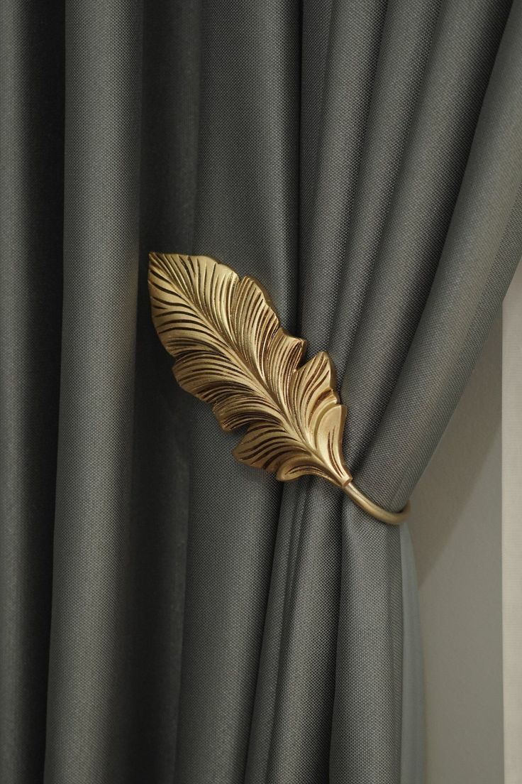 a gold leaf is hanging on the curtain in front of a gray drapeside