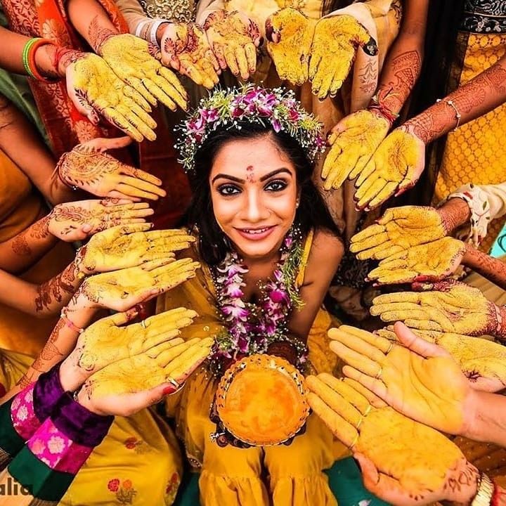 a woman in yellow is surrounded by many hands