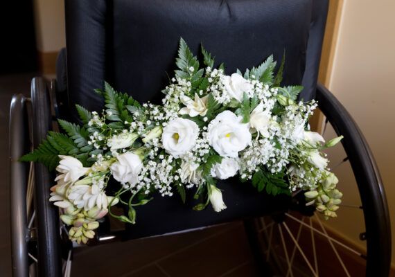 white flowers and greenery are arranged on a black pillow in a wheel chair,