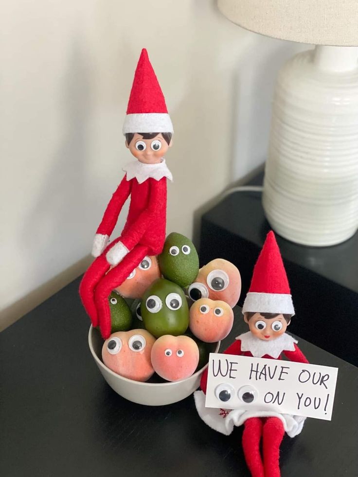 two elfs are sitting on a table with some fruit