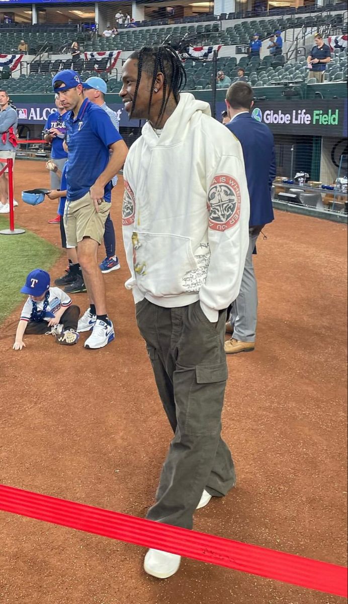 a man with dreadlocks walking across a baseball field