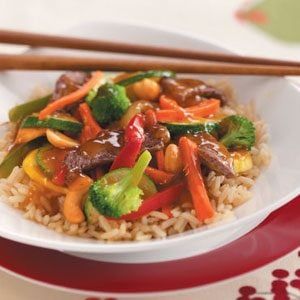 a white plate topped with rice and veggies next to chopsticks on a table