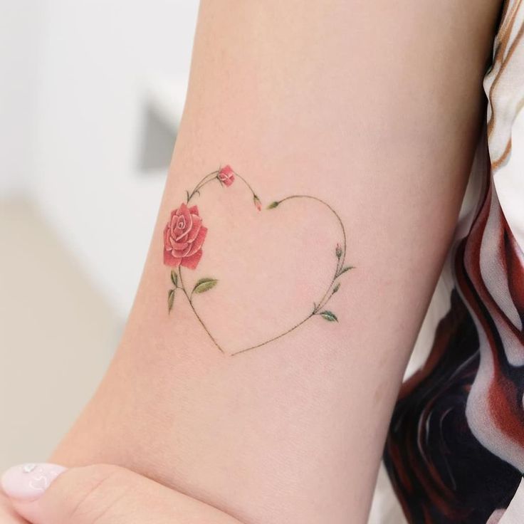 a woman's arm with a rose tattoo on the left side of her arm