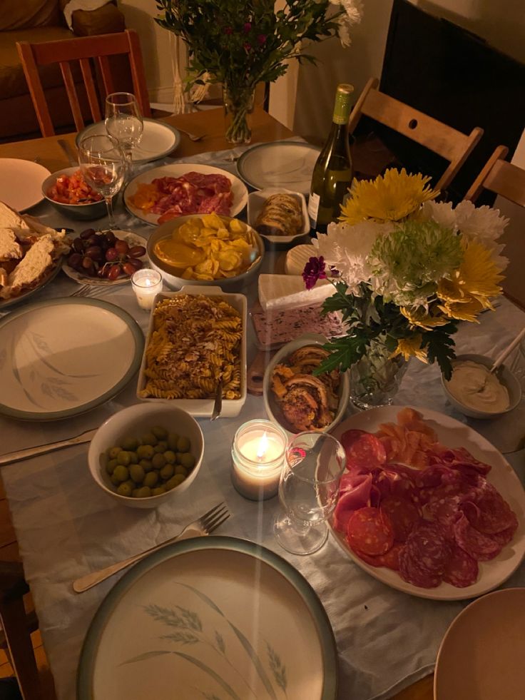 the table is set with many plates and bowls full of food, including meats