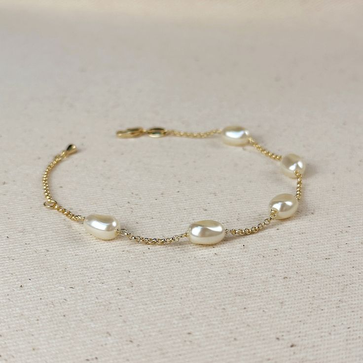 Indulge in the timeless beauty and sophistication of our 18k Gold Filled Spaced Baroque Pearl Bracelet. The perfect blend of elegance and delicacy, this classic piece exudes a luxurious charm that will elevate any outfit. Add a touch of opulence to your wardrobe and captivate with every turn of your wrist. * Metal: 18k Gold Filled * Width: 10mm Simulated Baroque Pearl  Beads * Size:  6.5 + 1 inch adjustment. * Hypoallergenic * Water-resistant * Handcrafted in Brazil Hand Chain Bracelet, 18k Gold Chain, Jewelry Lookbook, Hand Chain, Emerald Jewelry, Anklet Jewelry, Earrings Collection, Baroque Pearls, Chain Link Bracelet