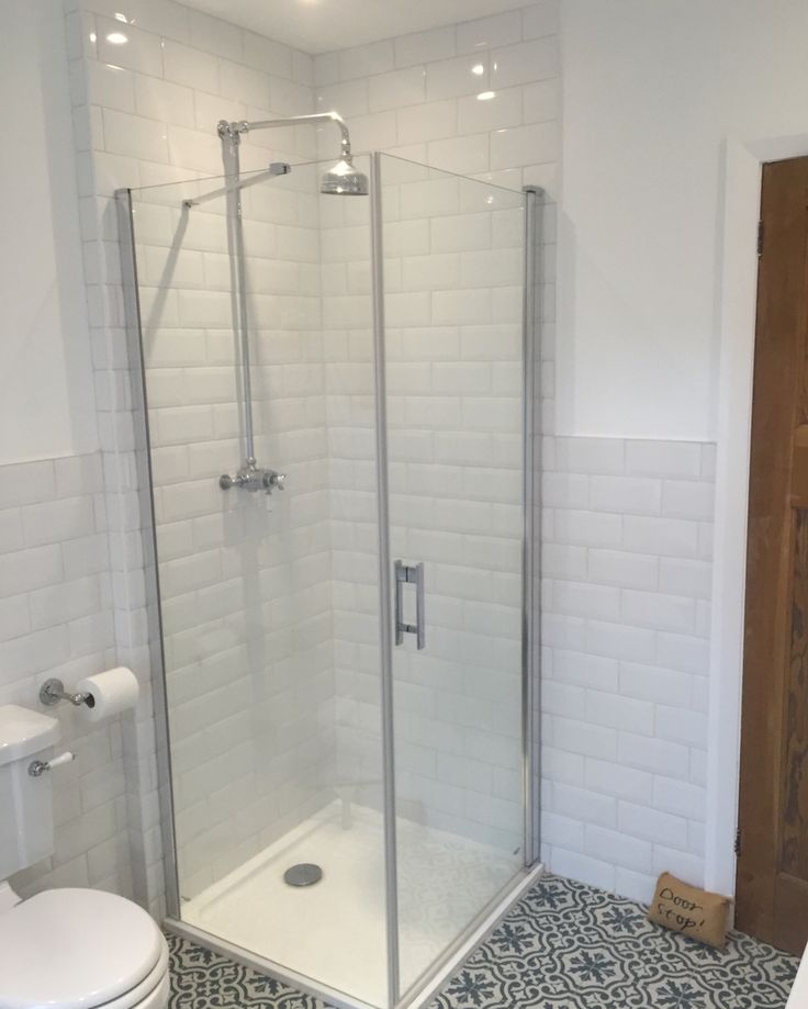 a bathroom with a walk in shower next to a white toilet and tiled flooring