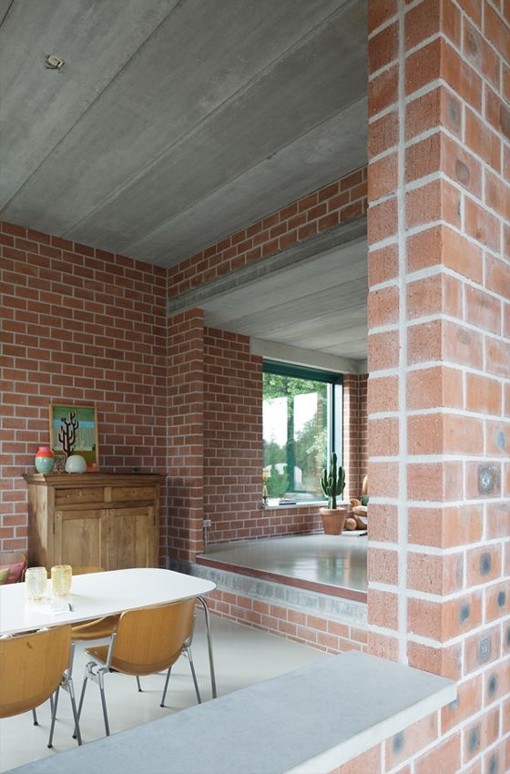 a dining room table and chairs in front of a brick wall with an open window