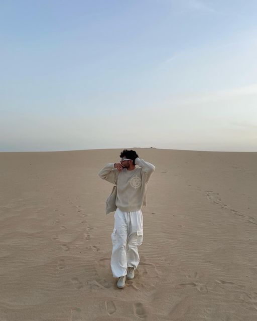 a man standing in the middle of a desert with his hands on his head and looking into the distance