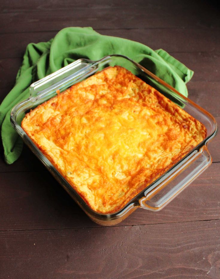 a casserole dish is sitting on a wooden table with a green cloth around it