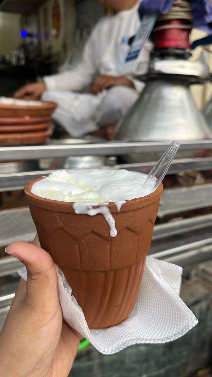 a person holding up a chocolate cup with whipped cream on it