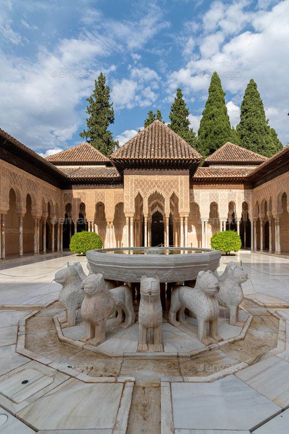 an outdoor fountain in the middle of a courtyard with arches and trees on either side