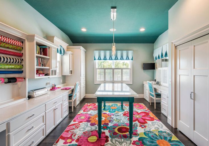 a kitchen with white cabinets and colorful rugs on the floor in front of windows