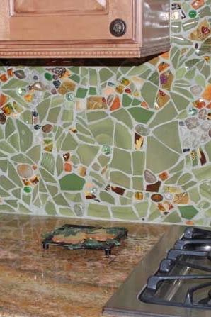 a stove top oven sitting inside of a kitchen next to a wall covered in mosaic tiles