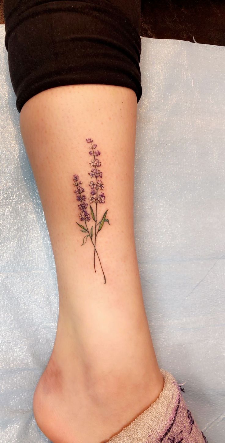 a woman's foot with a small flower tattoo on the left side of her leg