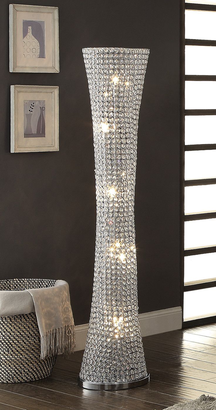 a tall silver vase with lights on it in a living room next to a chair