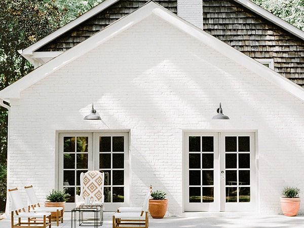 a white house with chairs and tables in front of the doors, windows, and patio furniture